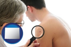wy map icon and a dermatologist examines a mole on a male patient