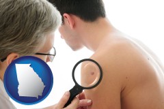 a dermatologist examines a mole on a male patient - with GA icon
